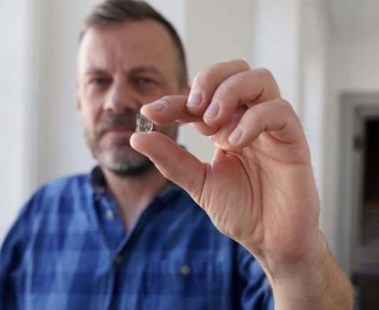 Senior Researcher at the National Museum of Denmark Mads Dengso Jessen holds a Viking Age window glass fragment. Source: John Fhær Engedal Nissen / National Museum of Denmark