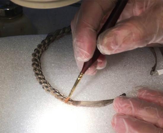 A piece of the Viking silver treasure hoardbeing cleaned by a conservator.      Source: Acta Konserveringscentrum AB