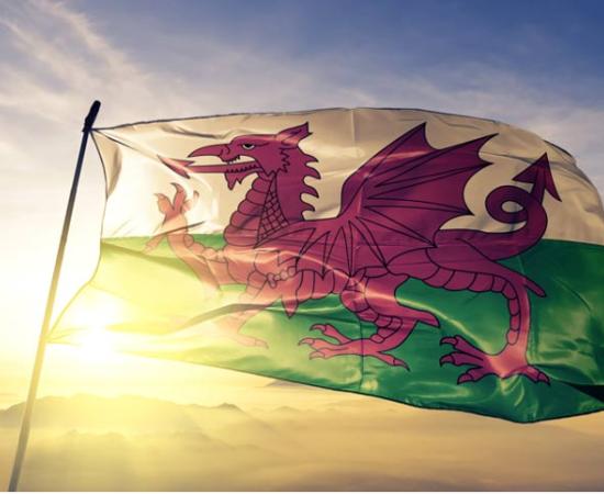 Wales Welsh flag waving on the top sunrise mist fog.  Source: Oleksii/Adobe Stock