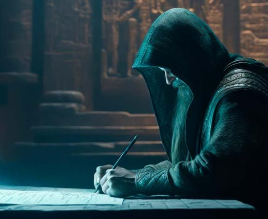 A hooded scribe working on an ancient manuscript.  Source: UniverseInside / Adobe Stock