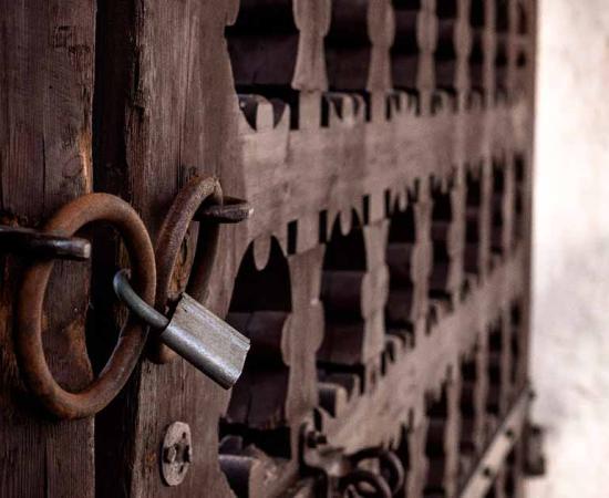 Old locked gate closed to a large castle. Source: Ekaterina / Adobe Stock