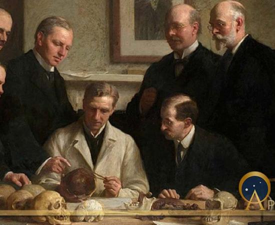 Group portrait of the Piltdown skull being examined by John Cooke in 1915. Back row: (left to right) F. O. Barlow, G. Elliot Smith, Charles Dawson, Arthur Smith Woodward. Front row: A. S. Underwood, Arthur Keith, W. P. Pycraft, and Sir Ray Lankester. Note the painting of Charles Darwin on the wall. (Public Domain).
