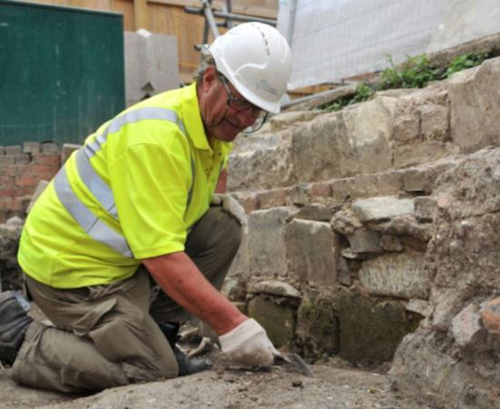 Cotswold Archaeology worker excavating in the area where the medieval graves and other artifacts were discovered. 