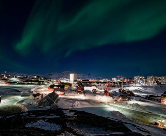 Nuuk, Greenland skyline with the aurora borealis shining overhead.