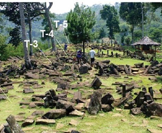 Grassy hilltop terrace scattered with dark columnar andesite blocks, with labels T-2 to T-5