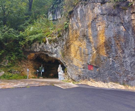 The rock face and arched entrance of the Isturitz and Oxocelhaya caves, with a paved road in front and trees above