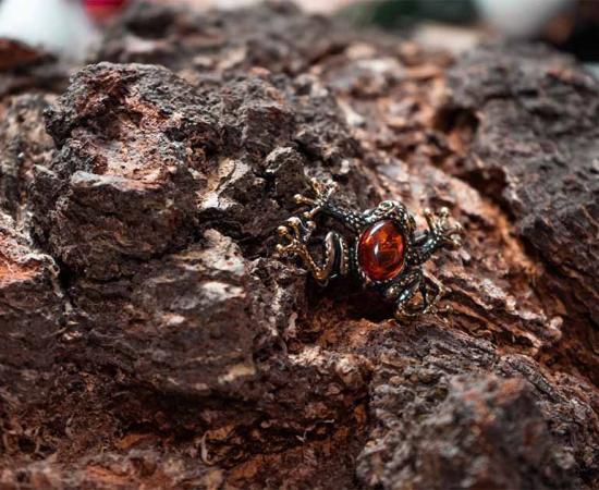 Frog brooch of amber and bronze on a rock, representative of living fossils.	Source: ISliM / Adobe Stock
