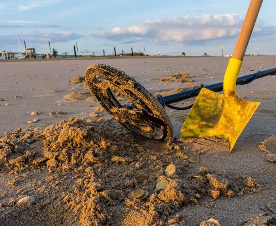 A metal detector and shovel on the beach with coins that might be rare medieval coins. You never know!        Source: andrewbalcombe / Adobe Stock