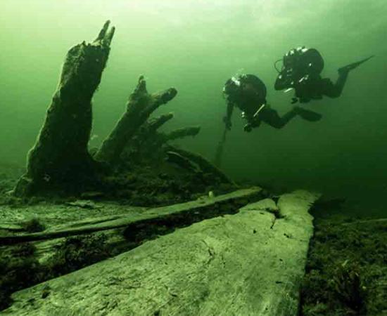 The authors at the stern of the wreck where the standing bottom logs and stern are seen sticking up from the seabed, seen from the starboard side. Source: Florian Huber/Stockholm University.