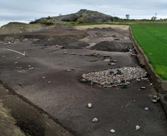 Rounded stone blocks forming an arc (in the foreground), cairn and monolithic alignment at Veyre-Monton, France.   Source: Denis Gliksman, INRAP