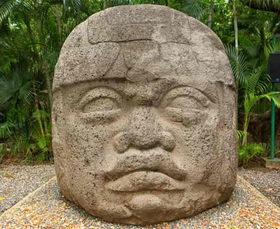 Large pre-Hispanic Olmec basalt carved head in the La Venta archeological park in Villahermosa Mexico.	Source: Barna Tanko