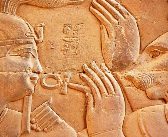 Relief carved from stone featuring Ptolemy XIII of Egypt and the deity Isis. Representational image.  