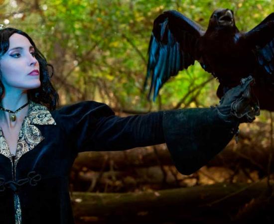A female, crowned, royal occult practitioner with a magical raven. Source: Petro / Adobe Stock