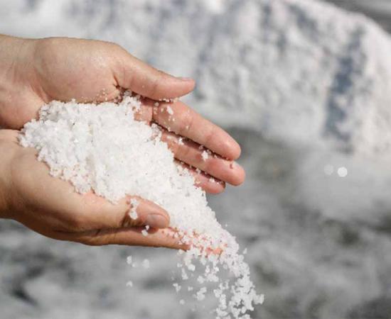 Hands sprinkling salt. Humans have cultivated salt for centuries, but in some places, salt has covered the earth. Source: Left zlikovec / Adobe Stock