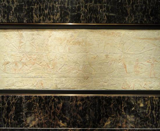 A limestone relief carved with rows of offering bearers and hieroglyphs from an Old Kingdom tomb at Saqqara