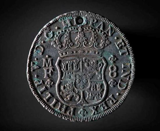 Pillar dollar, 8 reals and minted in Mexico. At the top there is a small hole, probably used to sew the coin into clothing.