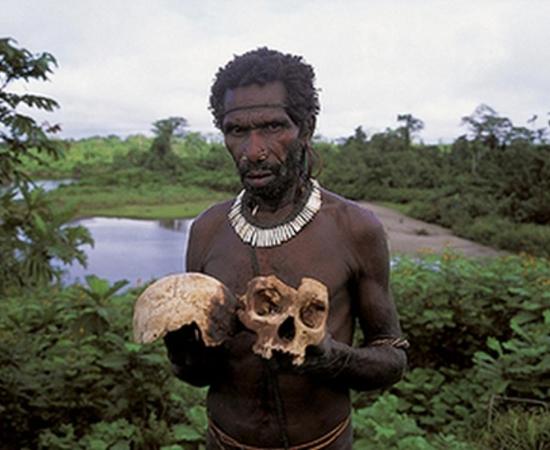 A Fore tribesman of Papua New Guinea holding a skull 