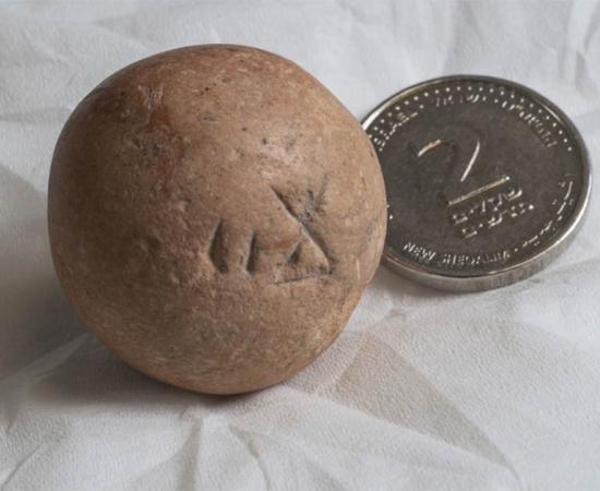 The ancient two-shekel weight, recently found near the Western Wall in Jerusalem, next to a modern Israeli two-shekel coin.  Source: Shai Halevi / Israel Antiquities Authority