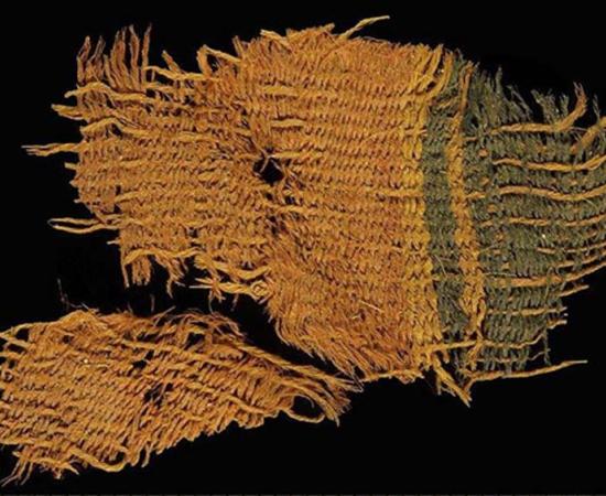 A fine wool textile dyed red and blue, found at Timna. The textile used the various colors of natural animal hair to create black and orange-brown colors for decorative bands. 