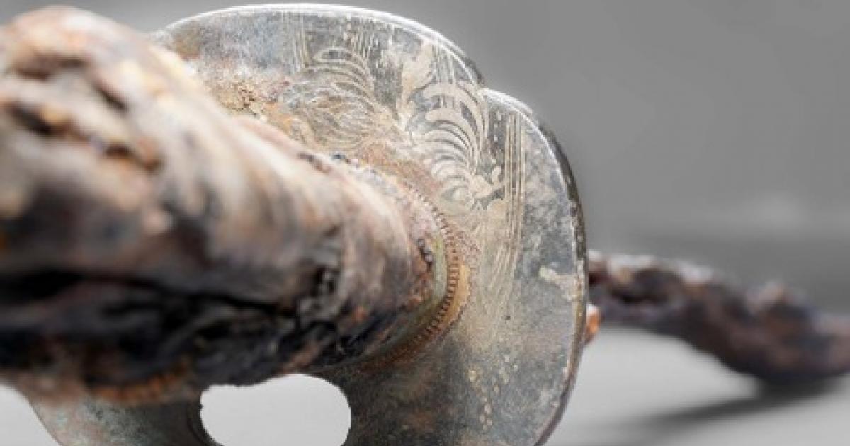 Detailed view of the Japanese swords guard plate (tsuba) with the inlaid and melted chrysanthemum motif and the water lines.