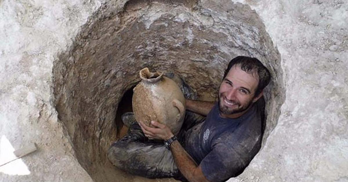 David Tanami, an Israel Antiquities Authority archaeologist, works his way into the narrow tomb opening to bring out a jar at a Canaanite burial site near Jerusalem's Biblical Zoo.