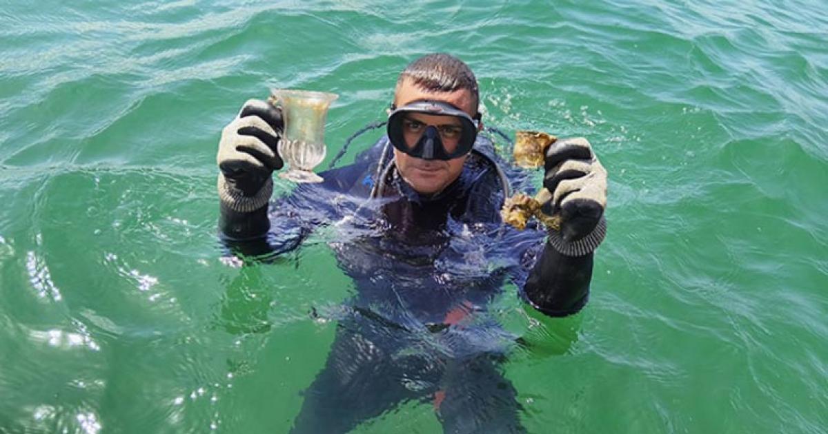 A marine archaeologist holds up intact glass vessels.	Source: Regional Historic Museum Burgas