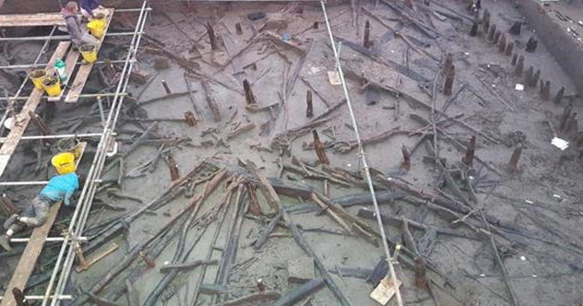 Archaeologists work from scaffolding to excavate a roundhouse that collapsed into the river after a fire. 
