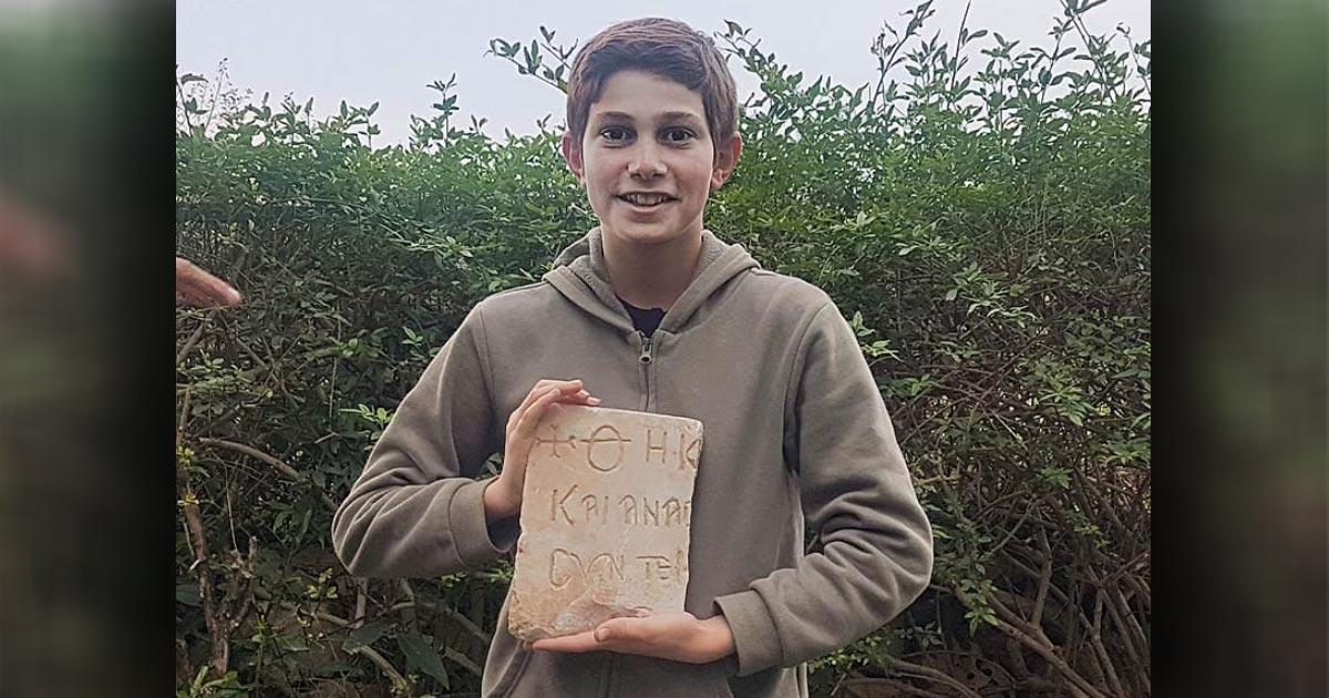Stav Meir, holding the 1,500-year-old Byzantine inscription that he discovered near Caesarea.	Source: Karem Said/ Israel Antiquities Authority