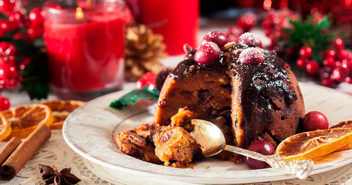 Christmas Pudding on a plate surrounded by candle and decorations.	Source: Sławomir Fajer/Adobe Stock