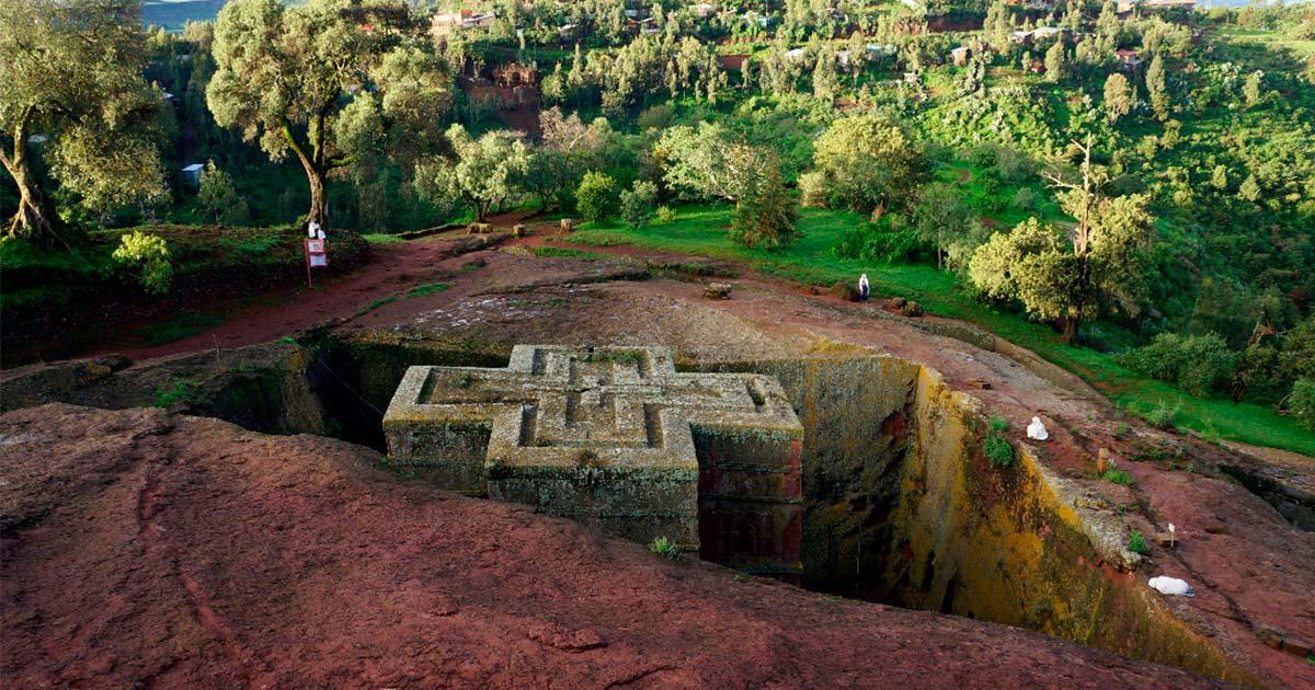 Top down view of an Ethiopian Church Forest in the early morning.  Several white-robed worshipers around the church.  Source: Gregory/Adobe Stock