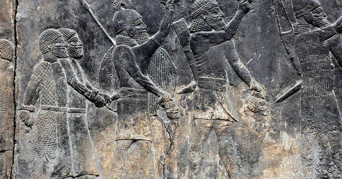 Assyrian soldiers carry beheaded heads of their prisoners as depicted on a wall in the South-West Palace at Nineveh, during the “First” Fall of Neneveh.          Source: Osama Shukir Muhammed Amin / CC BY-SA 4.0