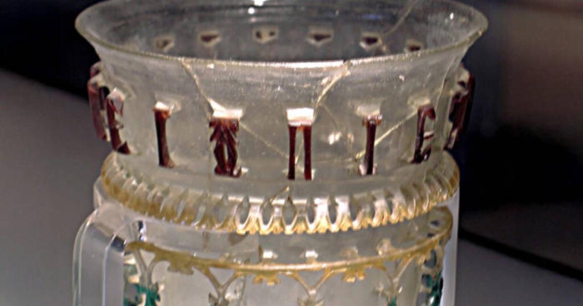 Glass openwork vessel from 300–350 AD with inscription and symbol.