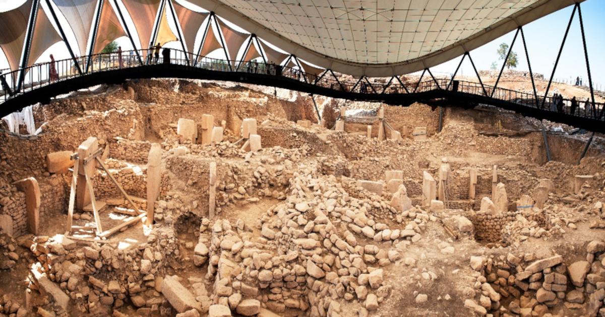 Visitors overlook the Göbekli Tepe excavation site beneath its protective roof. 