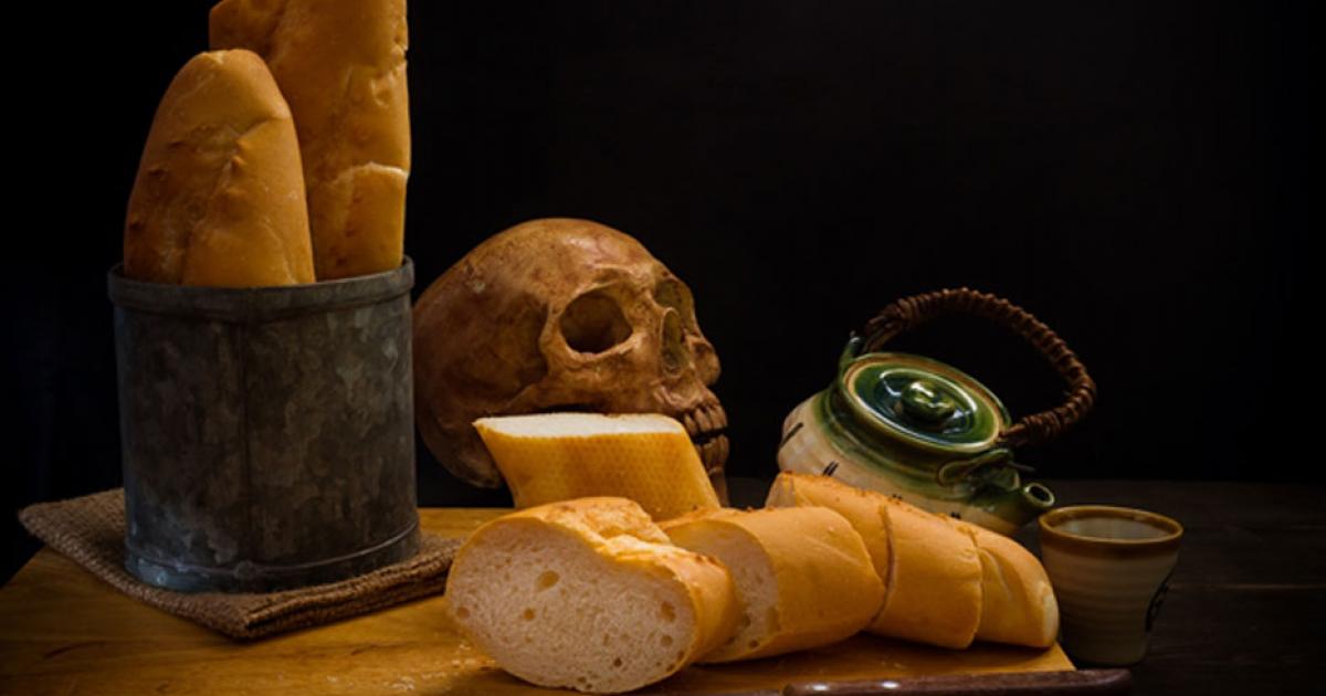 Grinding bones into bread - human skull and fresh bread.