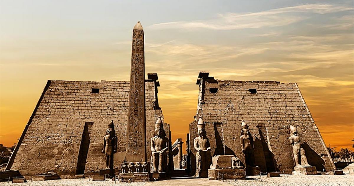 Entrance to the Luxor Temple at sunset showing the obelisk and statues of pharaohs