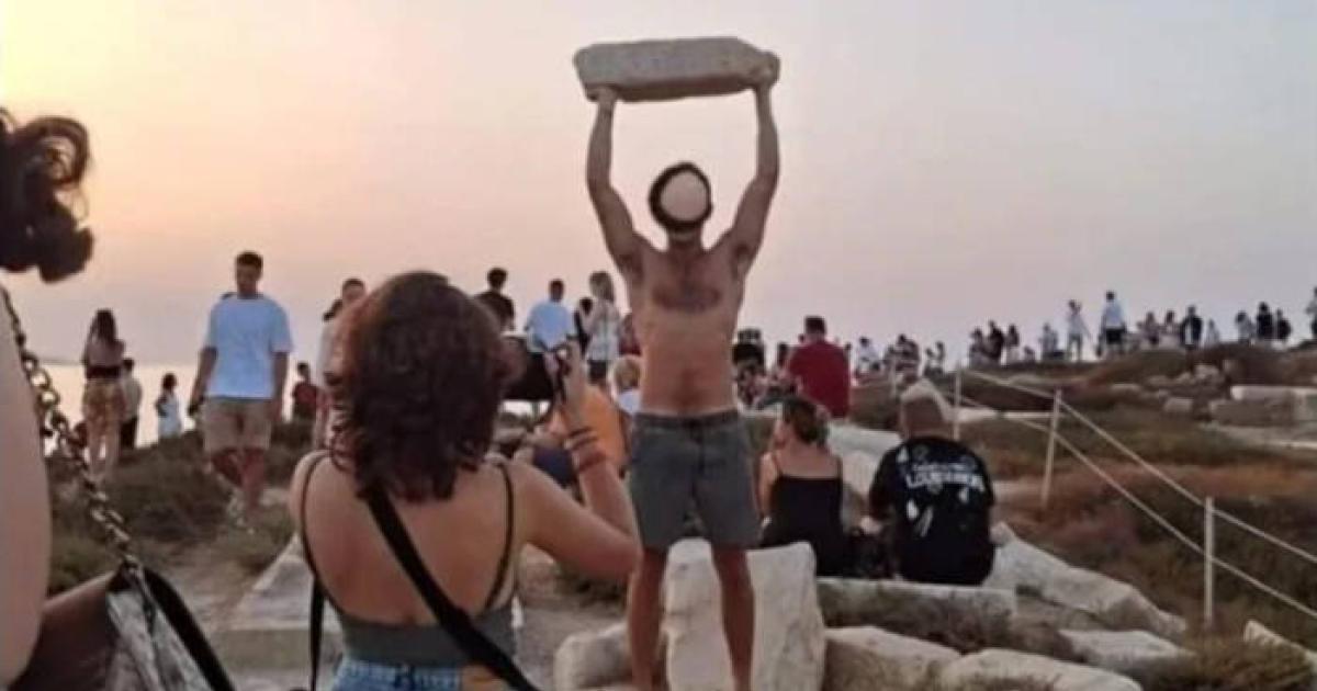 Tourist hold ancient stone aloft at Naxos, Greece.