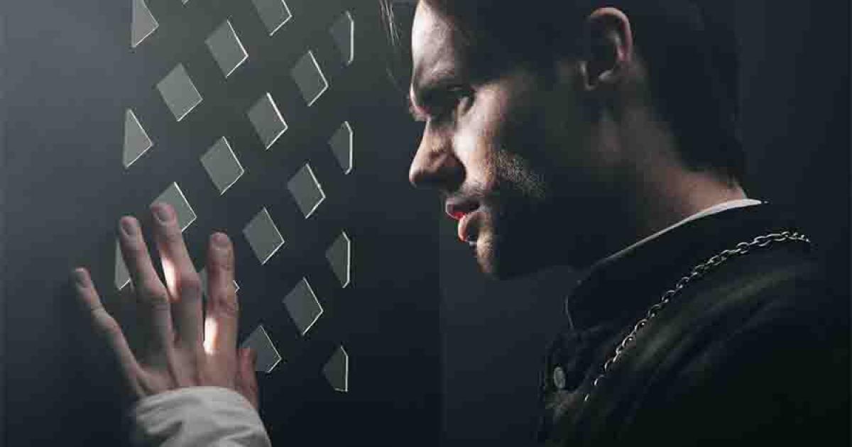 A young priest listens to confession. 