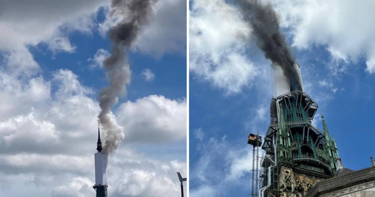 Tower of Rouen Cathedral billows smoke.