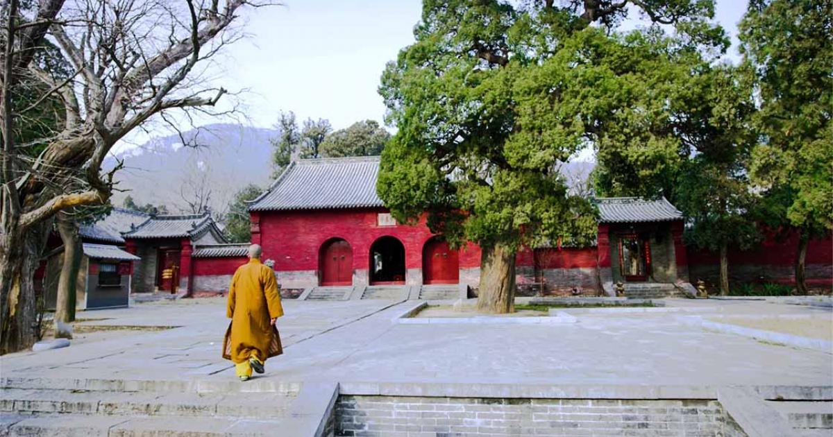 A modern monk walks into Shaolin Temple, famous for its kung-fu warriors, located in the high mountains of Henan, China. Source: Daniel / Adobe Stock