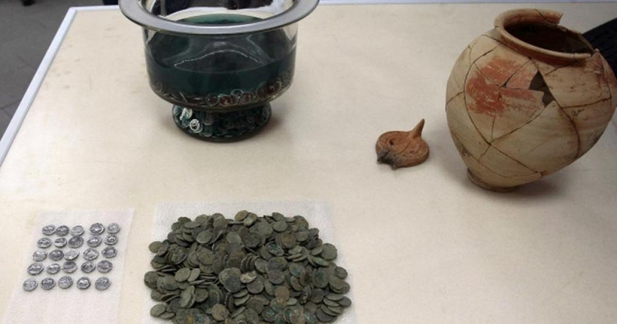 The ancient Roman coins, dating to the 1st century AD alongside the clay vessel in which they were found; the owner’s name is inscribed on the vessel. 