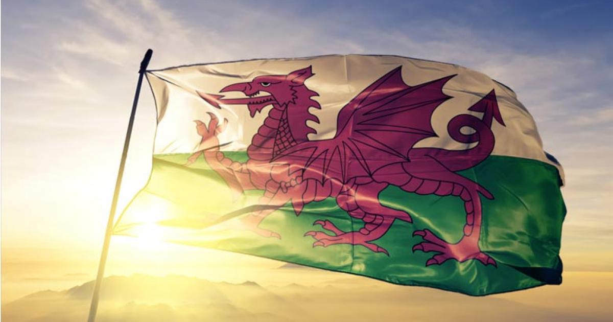 Wales Welsh flag waving on the top sunrise mist fog.  Source: Oleksii/Adobe Stock