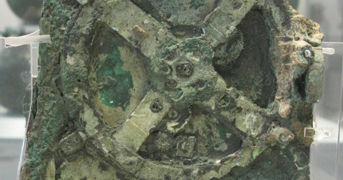 Corroded green bronze fragment with a large four-spoked gearwheel