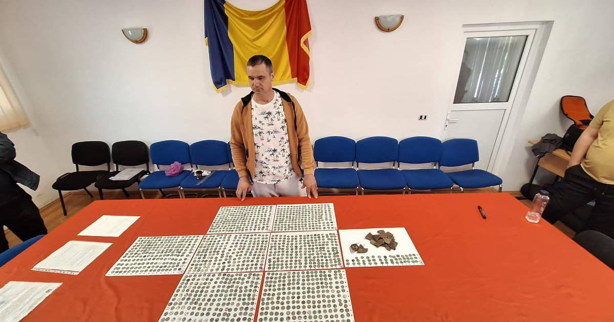 Roman metal detectorist Marius Mangeac stands in front of the Roman coins he discovered near the village of Letţa Veche.