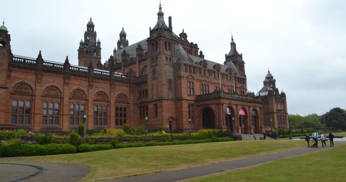 Red sandstone exterior of Kelvingrove Art Gallery and Museum behind a lawn