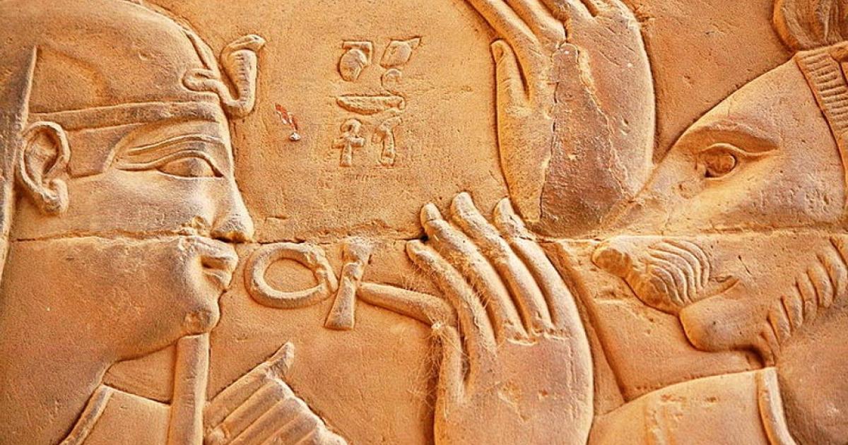 Relief carved from stone featuring Ptolemy XIII of Egypt and the deity Isis. Representational image.  