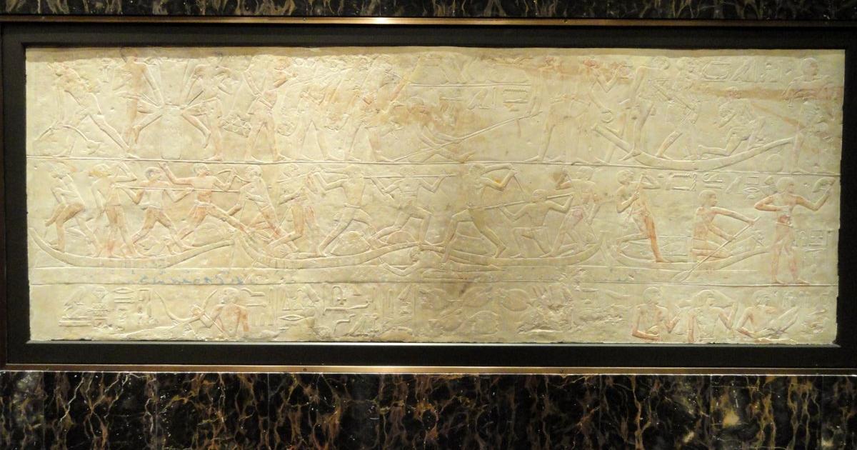 A limestone relief carved with rows of offering bearers and hieroglyphs from an Old Kingdom tomb at Saqqara