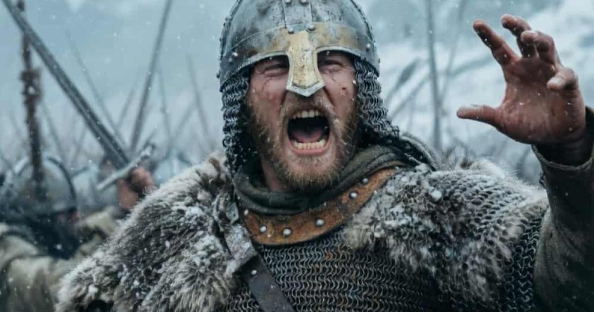 A fierce Viking warrior shouts a war cry mid-battle on a chaotic, snowy field.