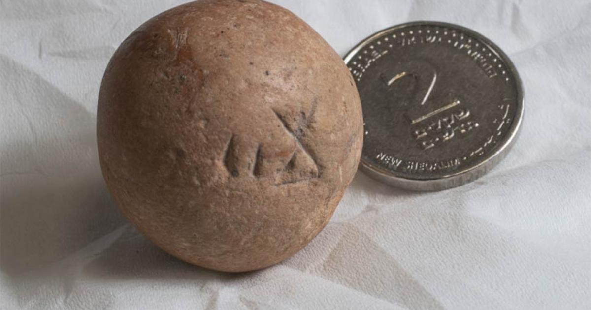 The ancient two-shekel weight, recently found near the Western Wall in Jerusalem, next to a modern Israeli two-shekel coin.  Source: Shai Halevi / Israel Antiquities Authority