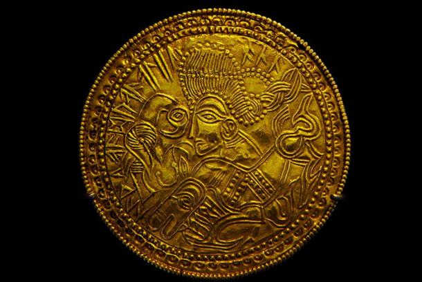 A Migration Period Germanic gold bracteate featuring a depiction of a bird, horse, and stylized head wearing a Suebian knot sometimes theorized to represent the Germanic god Wōden. As the Roman Empire began to decline there were several migrations into their territory by Germanic tribes and the Huns, people the Romans called barbarians. (Bloodofox/CC BY SA 3.0)