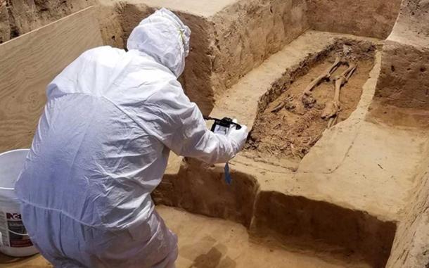 An archaeologist investigates the burial while wearing a suit that will minimize contamination to the historical site. (Jamestown Rediscovery)